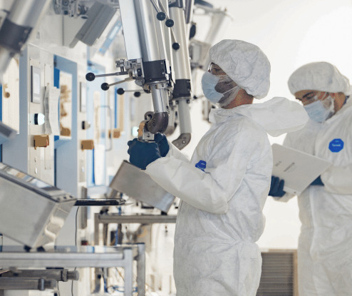 Technicians in protective suits working at a glovebox